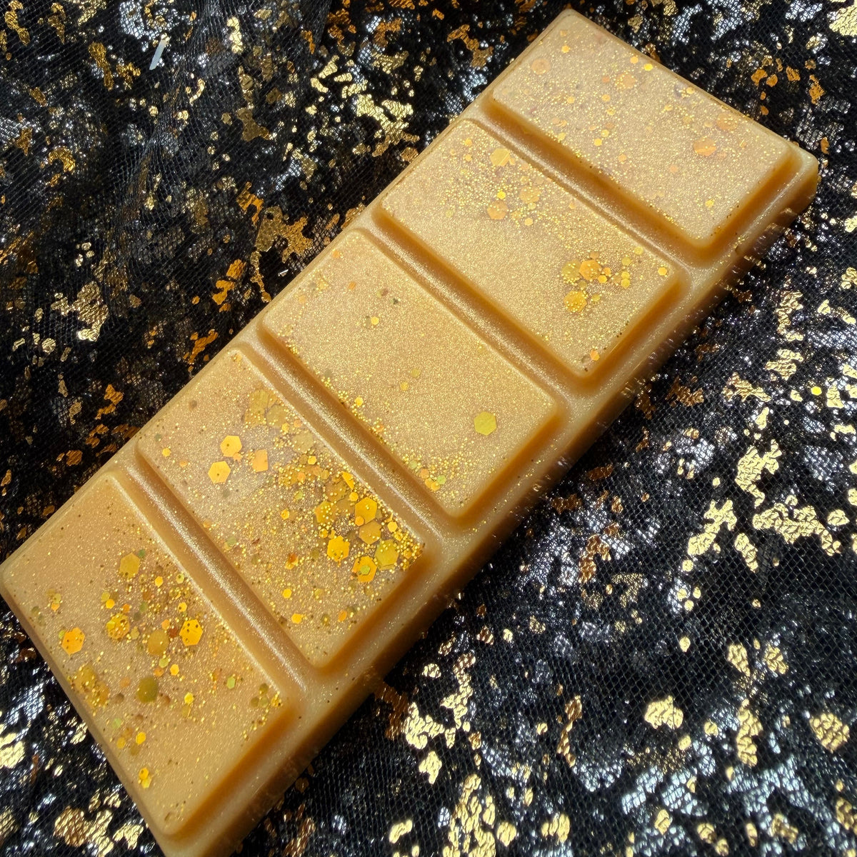Full Roary Night wax melt running diagonally from the lower left to the upper right on black and gold fabric, with larger glitter pieces across the lower two segments.