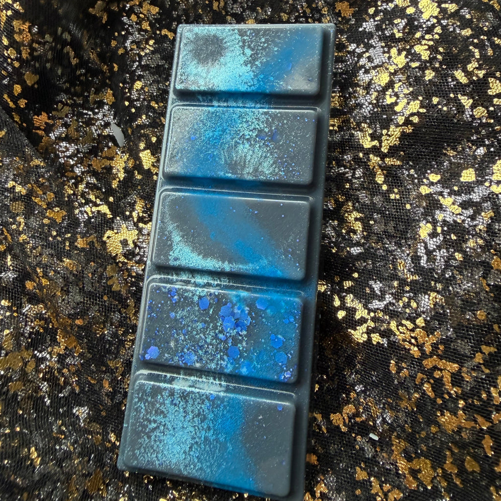 Darcy Vega wax melt photographed almost vertically without packaging, showing five dark blue sections with turquoise shimmer, a bright blue streak and chunky blue hexagonal glitter on the second section from the bottom.