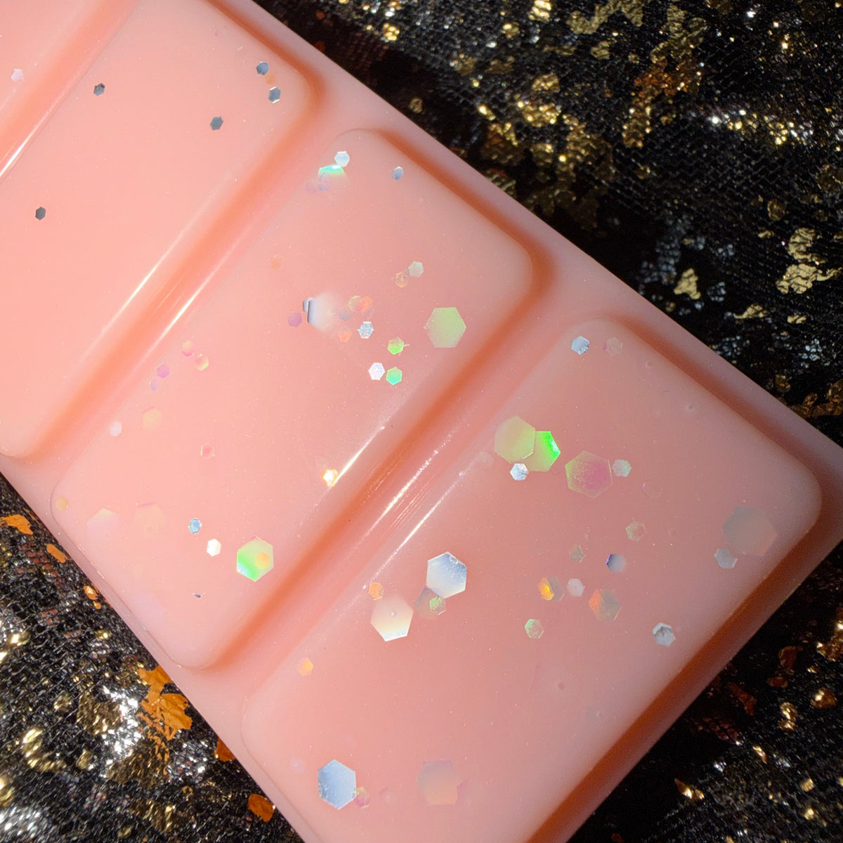Zoomed-in photograph of the Peachy Keen wax melt showing pale blue, pink and iridescent glitter reflecting against the peach-coloured wax.