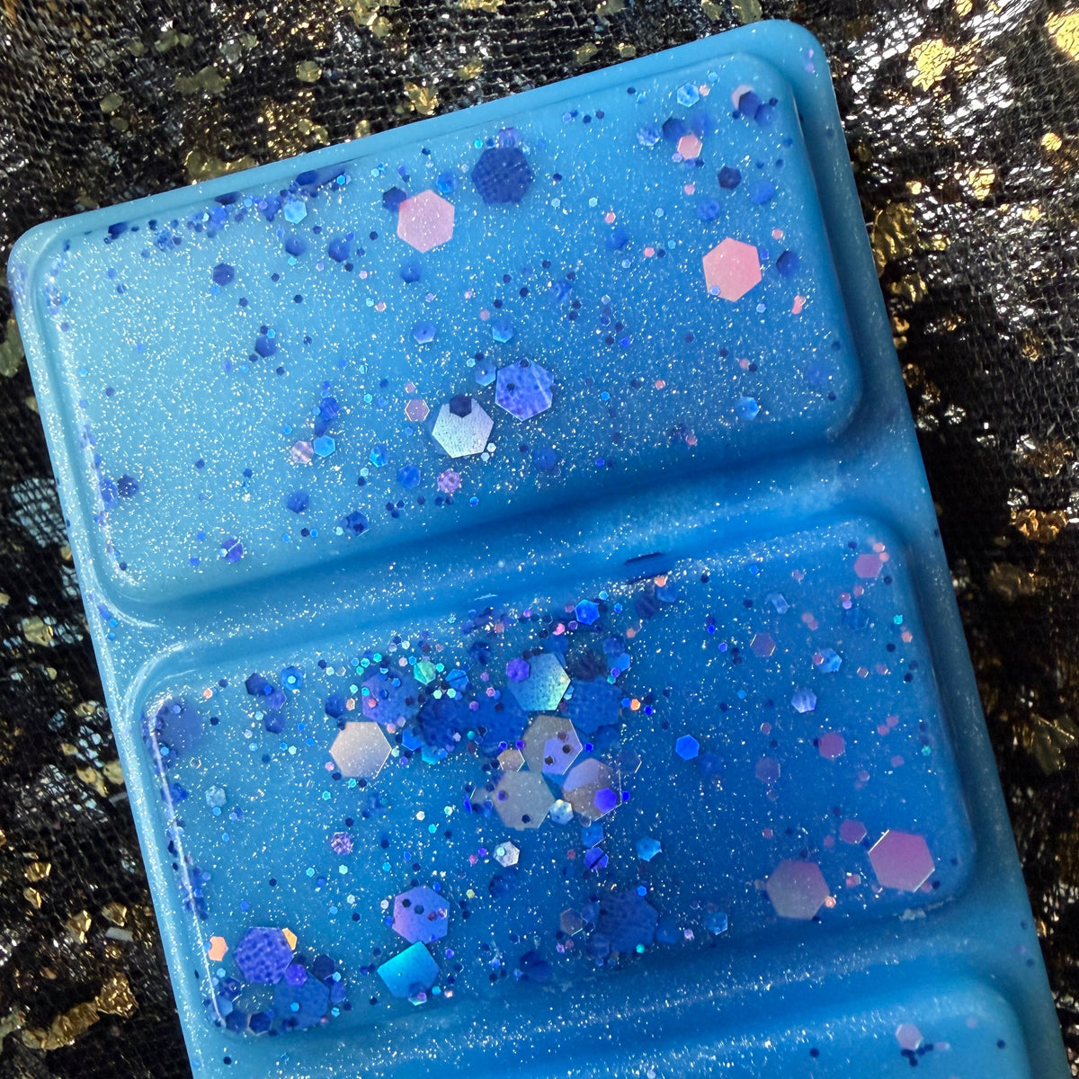 Detailed photograph of two Snowy Escape segments showing larger purple and pastel hexagonal glitter with fine iridescent shimmer.