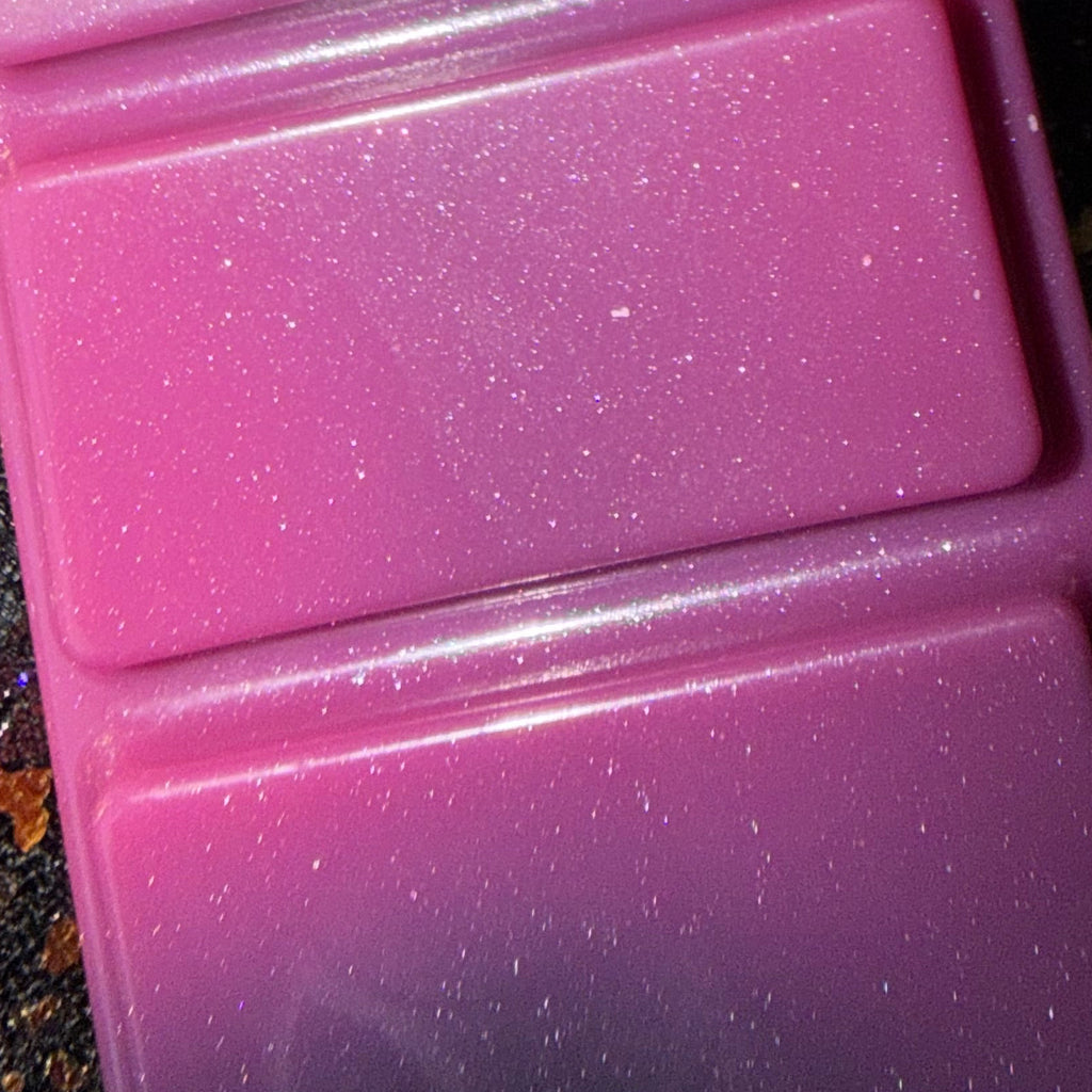 Zoomed-in photograph of the Joey wax melt showing a bright pink rectangular segment, fine pearlescent shimmer and dark grey marbling along its lower edge.