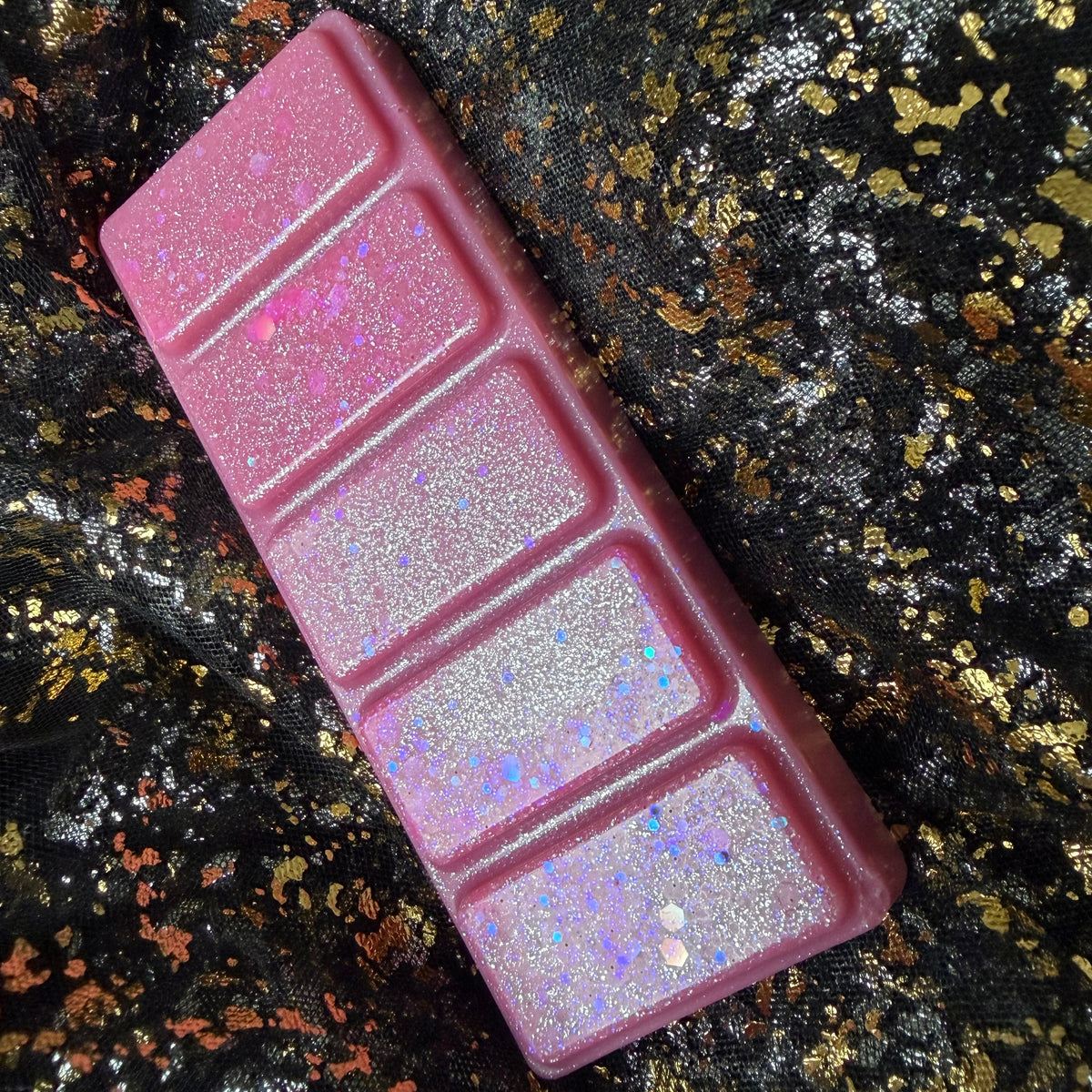 Side-angled photograph of the Flawless five-segment pink wax melt, showing the raised rectangular sections, rounded outer edge, silver iridescent shimmer and larger pink and holographic glitter pieces.