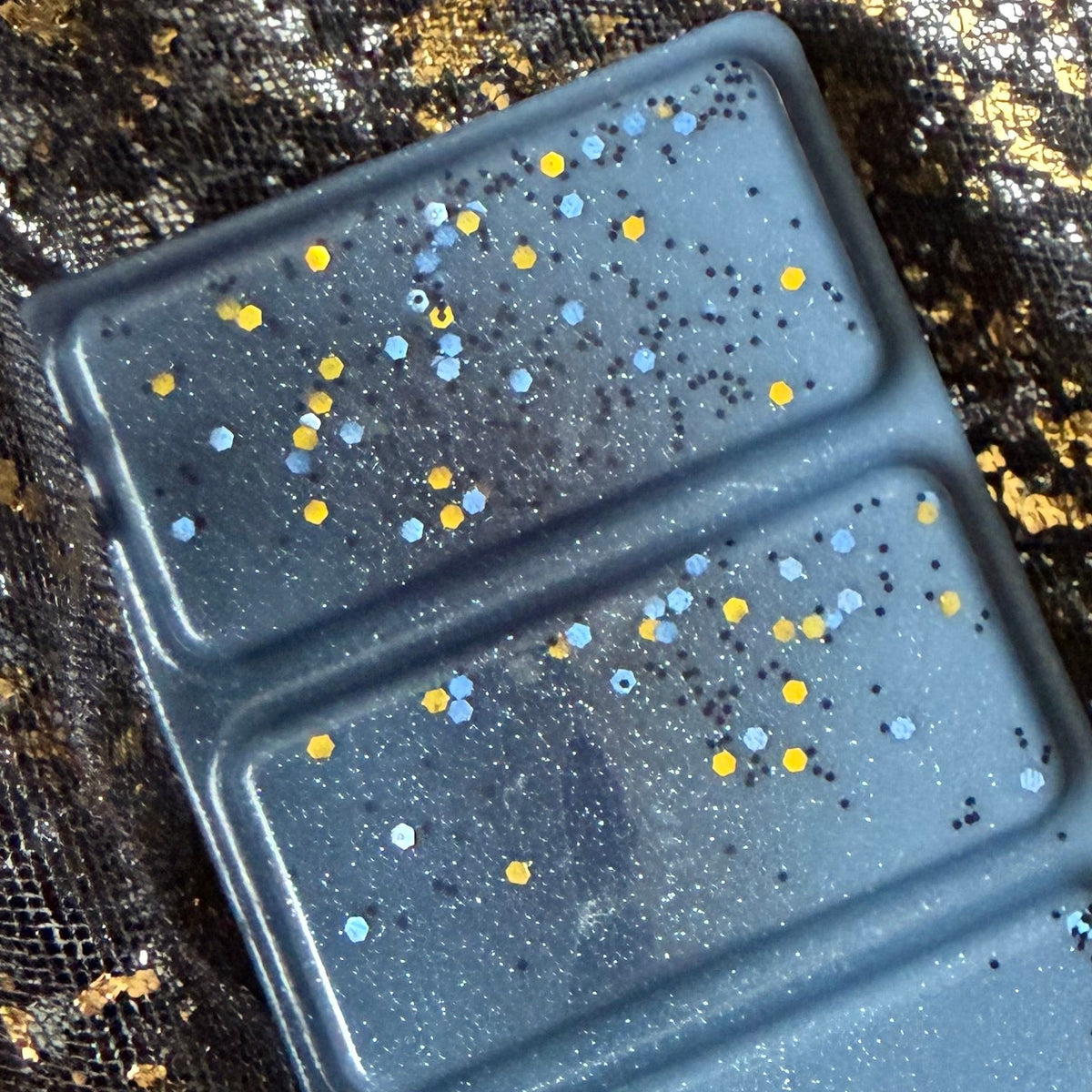 Detailed photograph of the central Morally Grey segments showing metallic gold circles, silver glitter and small black and blue pieces.