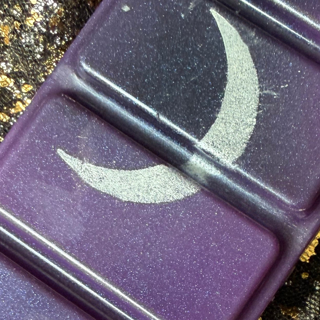 Close-up of the Lord of Shadow and Blood wax melt showing a sweeping metallic silver crescent moon across two deep purple rectangular segments.
