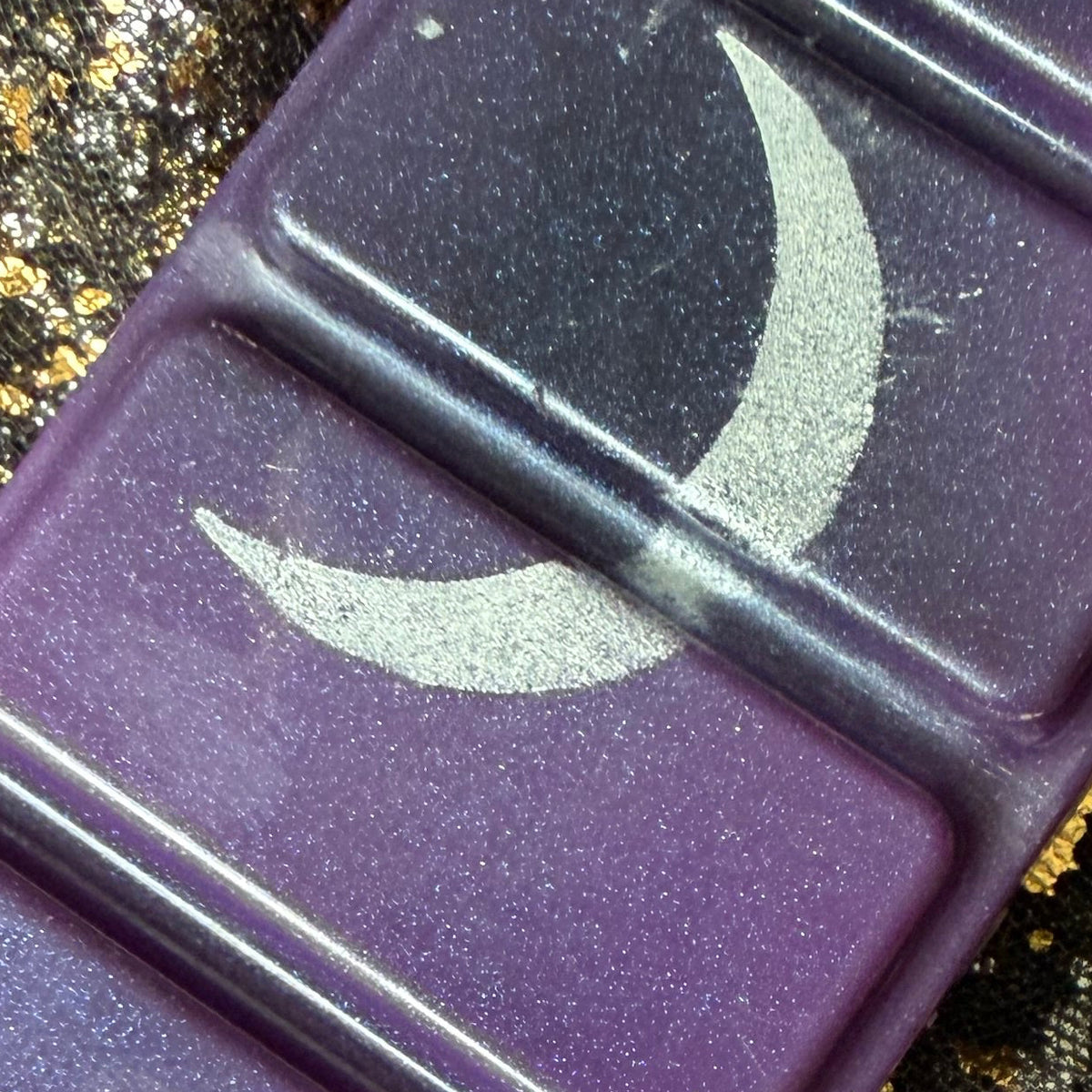 Close-up of the Lord of Shadow and Blood wax melt showing a sweeping metallic silver crescent moon across two deep purple rectangular segments.