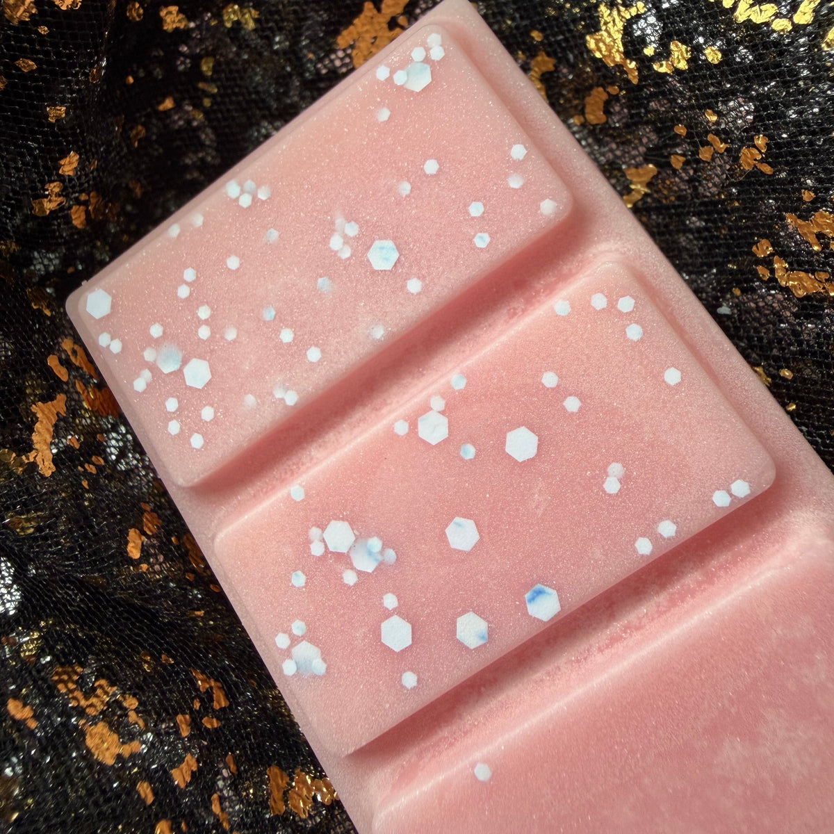 Zoomed-in photograph of the Petals of the Seer pink wax melt showing silver shimmer and scattered holographic glitter across its raised rectangular segments.