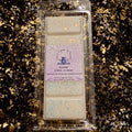 A packaged wax melt set from Xavier Forge Academy, featuring four rectangular wax melts with a lavender label, placed on a black and gold glittery background.