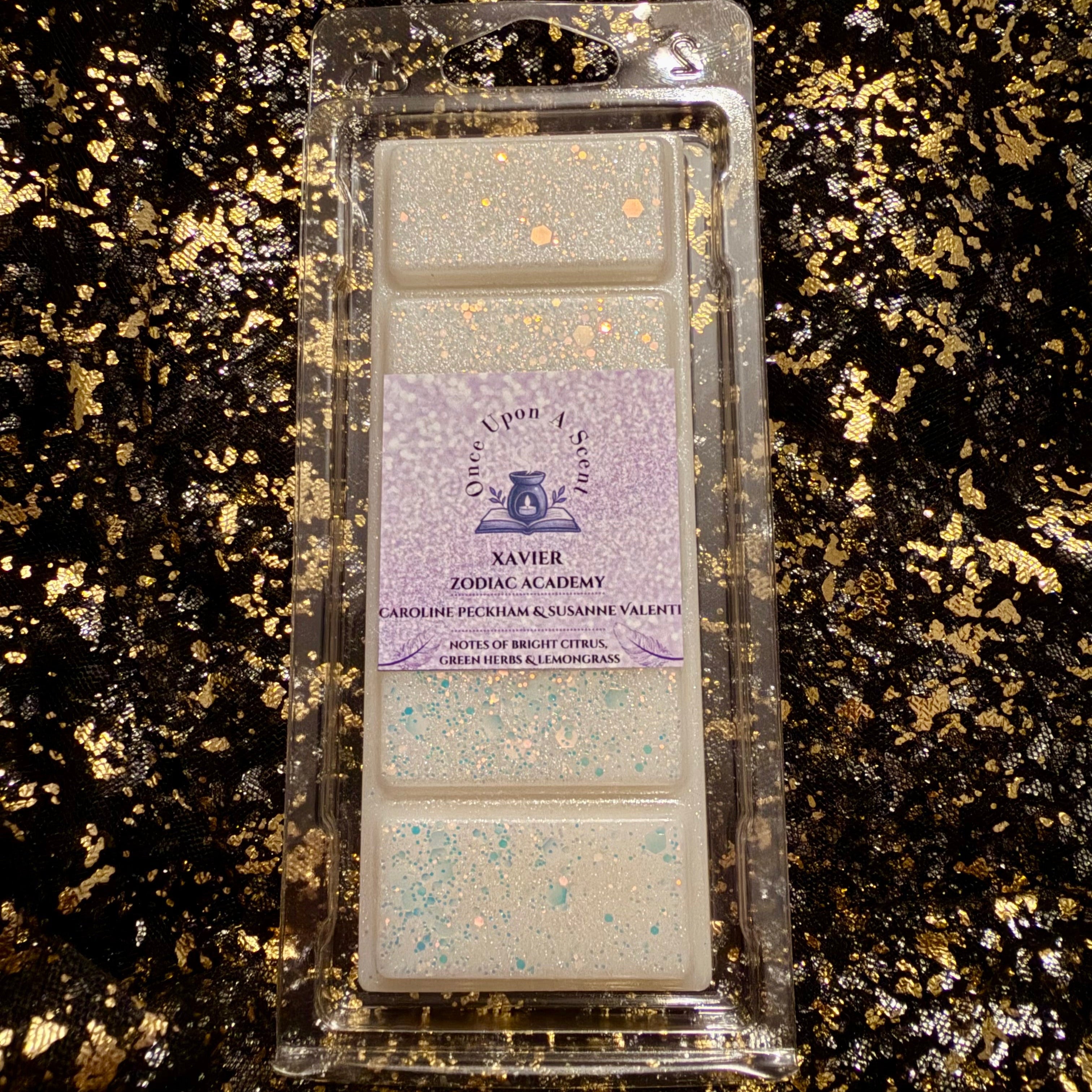A packaged wax melt set from Xavier Forge Academy, featuring four rectangular wax melts with a lavender label, placed on a black and gold glittery background.