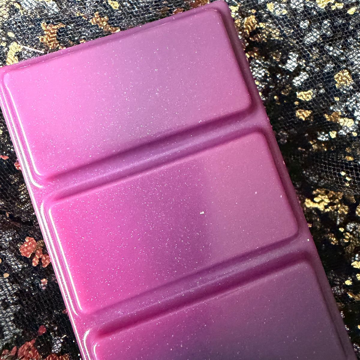 Close-up of the upper Joey wax melt segments, showing the bright pink colour, fine shimmer and a dark charcoal-grey section beginning beneath them.