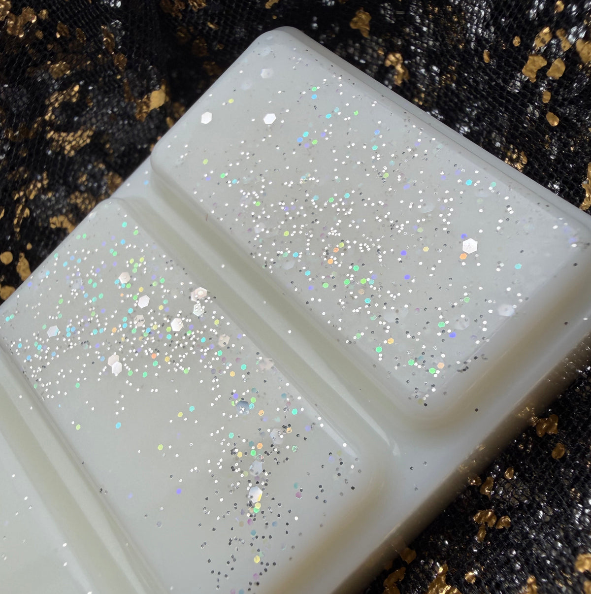 Close-up of two Boyfriend Hoodie wax melt segments showing silver, pastel blue, pink and iridescent glitter against creamy white wax.