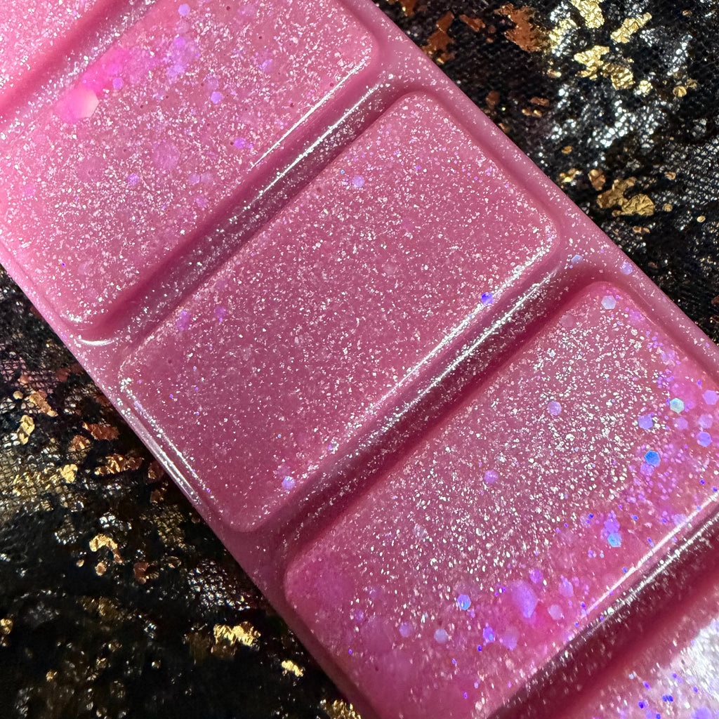 Close-up of the middle sections of the Flawless pink wax melt, showing dense silver shimmer, fine iridescent glitter and scattered pink and holographic confetti against black-and-gold fabric.