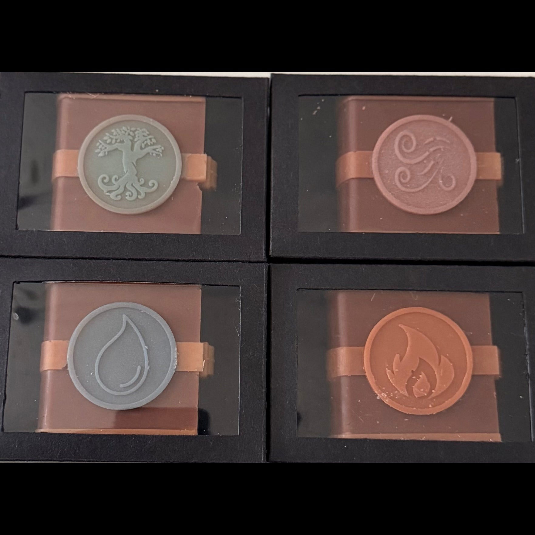 Four Zodiac Academy element wax melts in black boxes showing Fire Earth Air and Water spell book designs official Once Upon a Scent merchandise