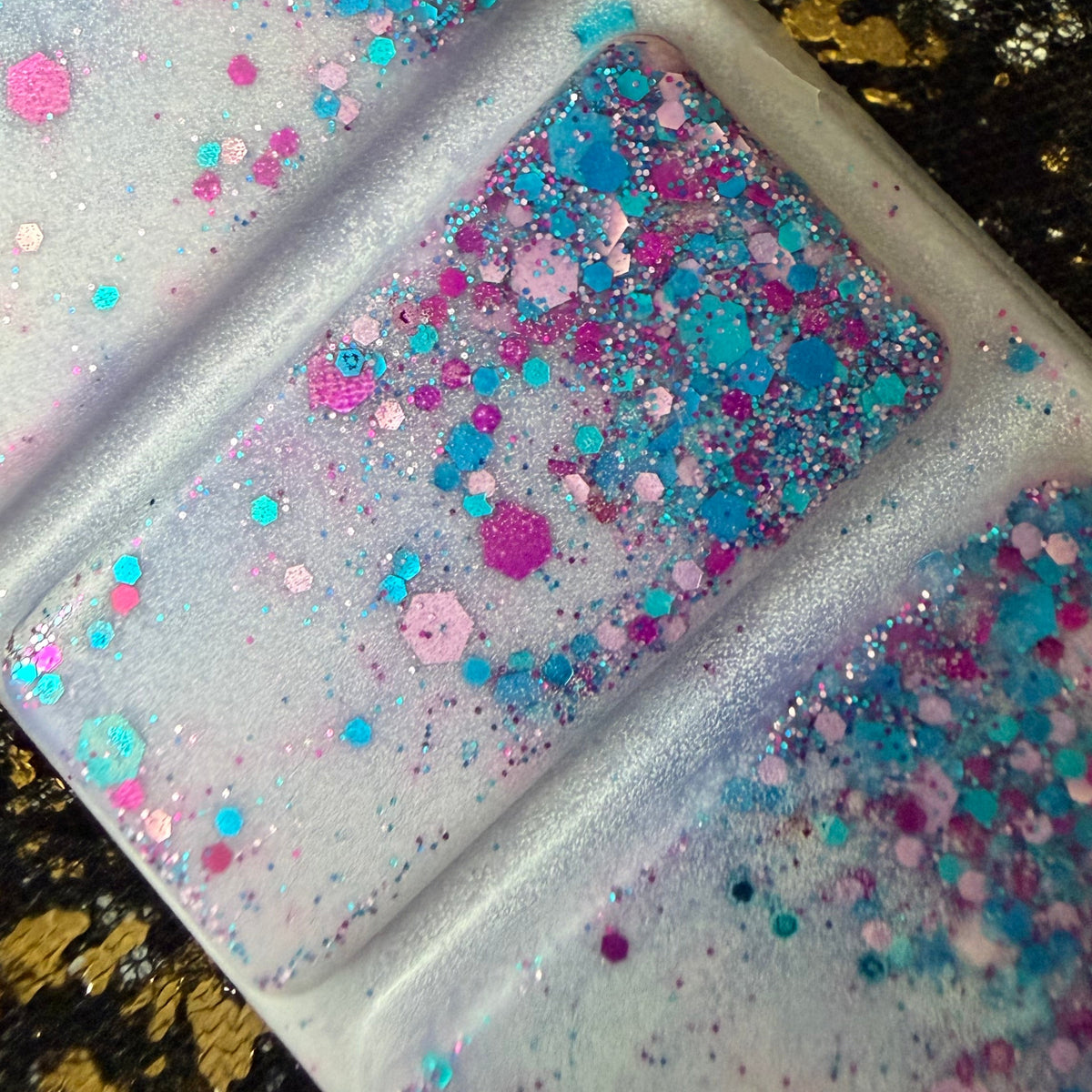  a close up of the older version  of the light purple coloured blackberry and bay leaf scented soy wax melt displaying the purple, pink and blue glitter. 