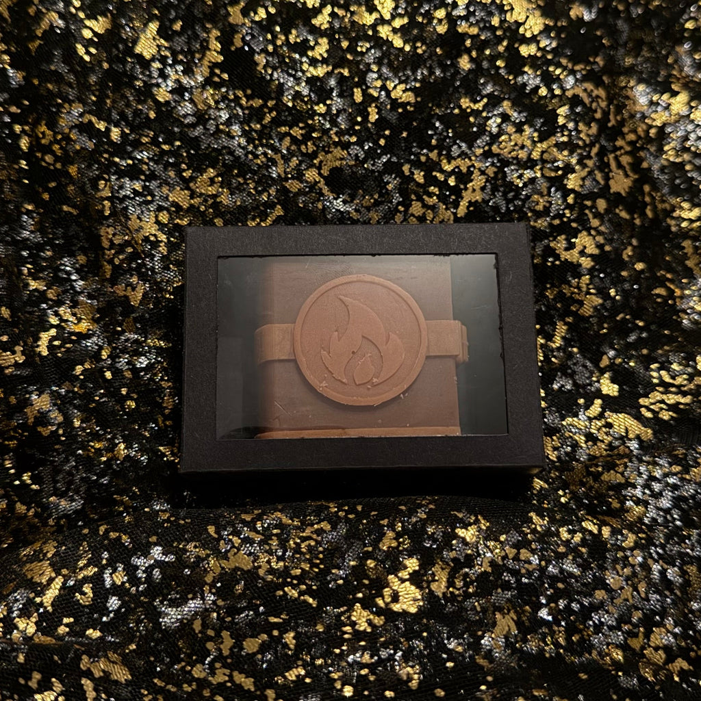 Zodiac Academy Fire Element House Ignus wax melt in black gift box with flame embossed spell book design on gold glitter background