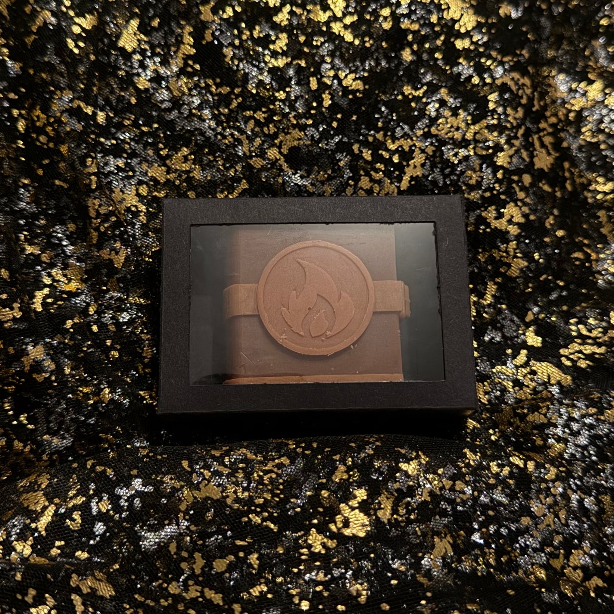Zodiac Academy Fire Element House Ignus wax melt in black gift box with flame embossed spell book design on gold glitter background