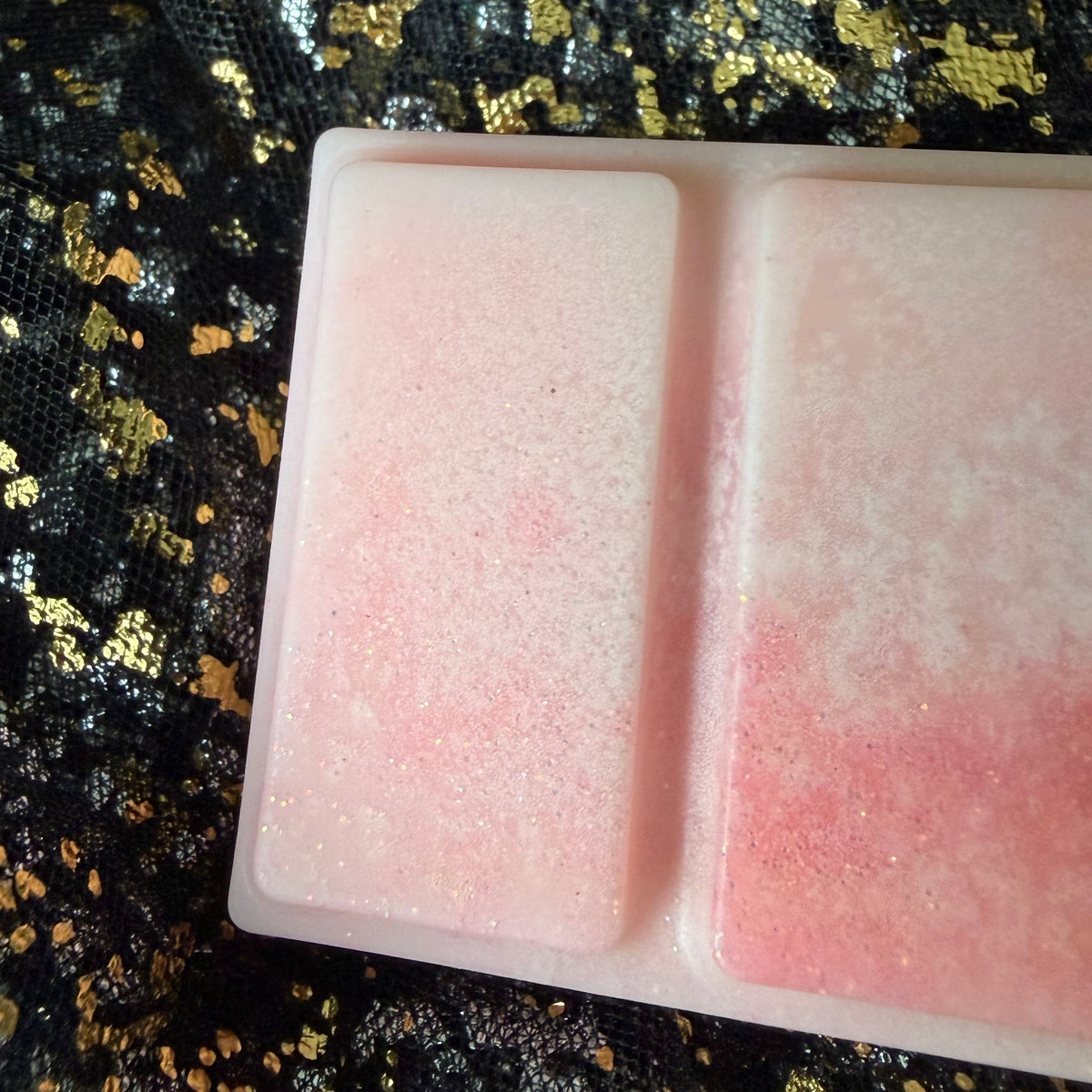 Close-up of two Rhubarb & Custard soy wax melt segments showing the soft transition from creamy white into pale pink.