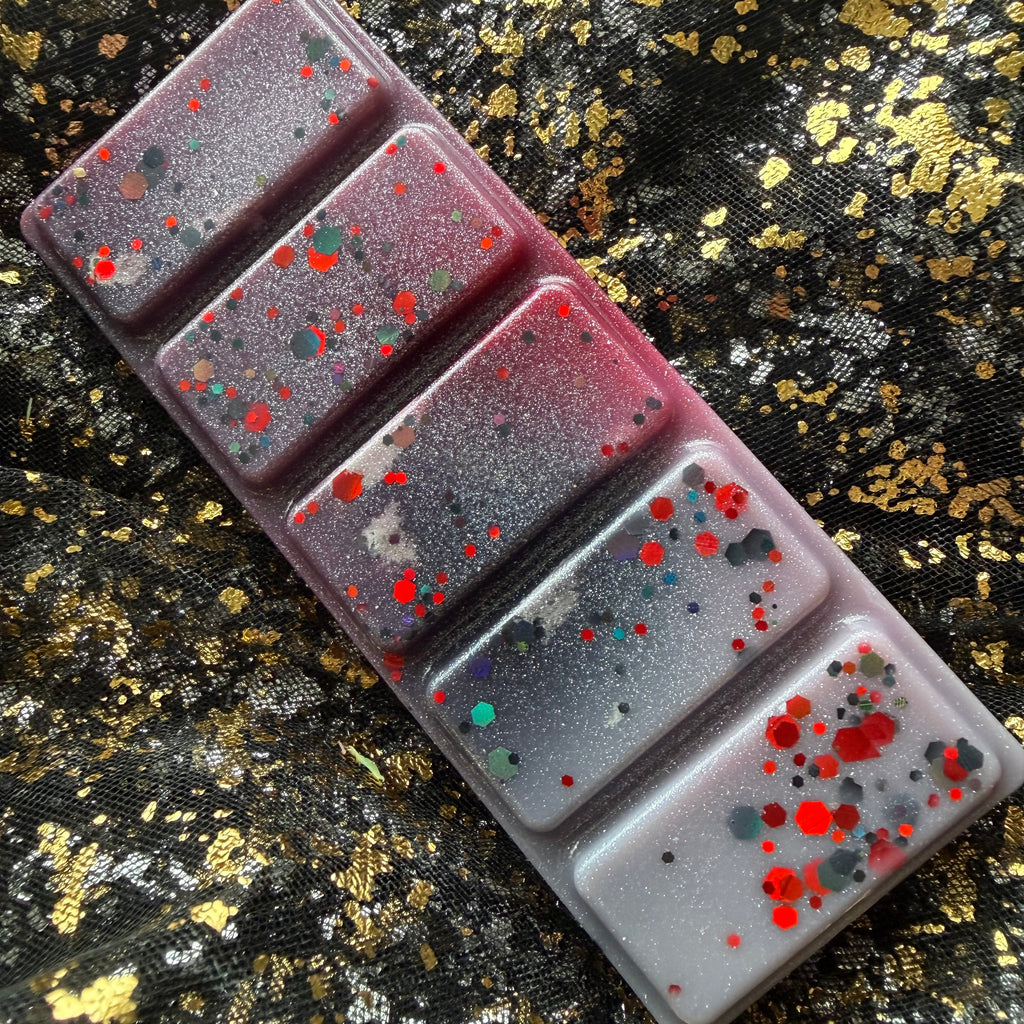 Full-length Thorns & Roses vegan soy wax melt scented with rose and oud, positioned diagonally on black-and-gold fabric, showing all five black, white and red marbled segments.