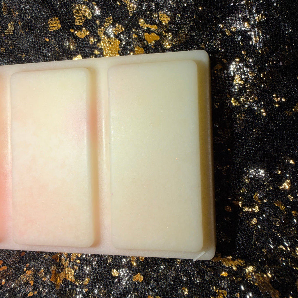 Close-up of the creamy white end of the Rhubarb & Custard wax melt, showing two raised rectangular segments with a faint pink tint along one edge.