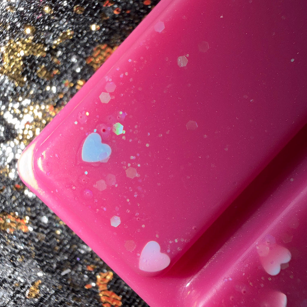 Close-up of a bright pink Midnight Wish wax melt segment showing pastel pink and iridescent heart-shaped glitter.