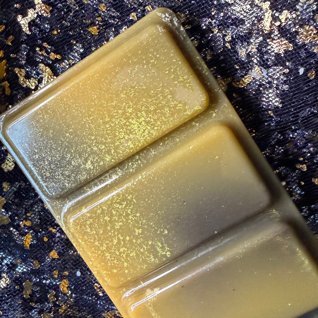 Angled close-up of the Lady of Light and Death soy wax melt scented with lavender and white musk showing three raised rectangular segments with blended gold, olive and smoky grey colouring.