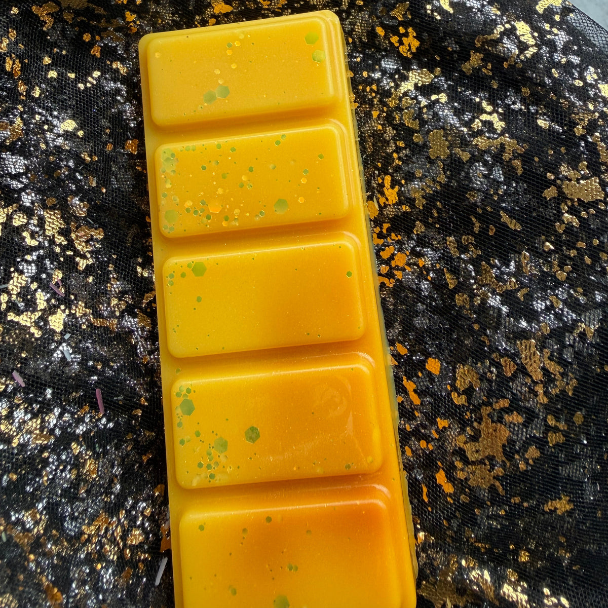 Close-up of the Summer Slow Burn wax melt showing the amber-coloured swirl running across the golden-yellow upper segment.