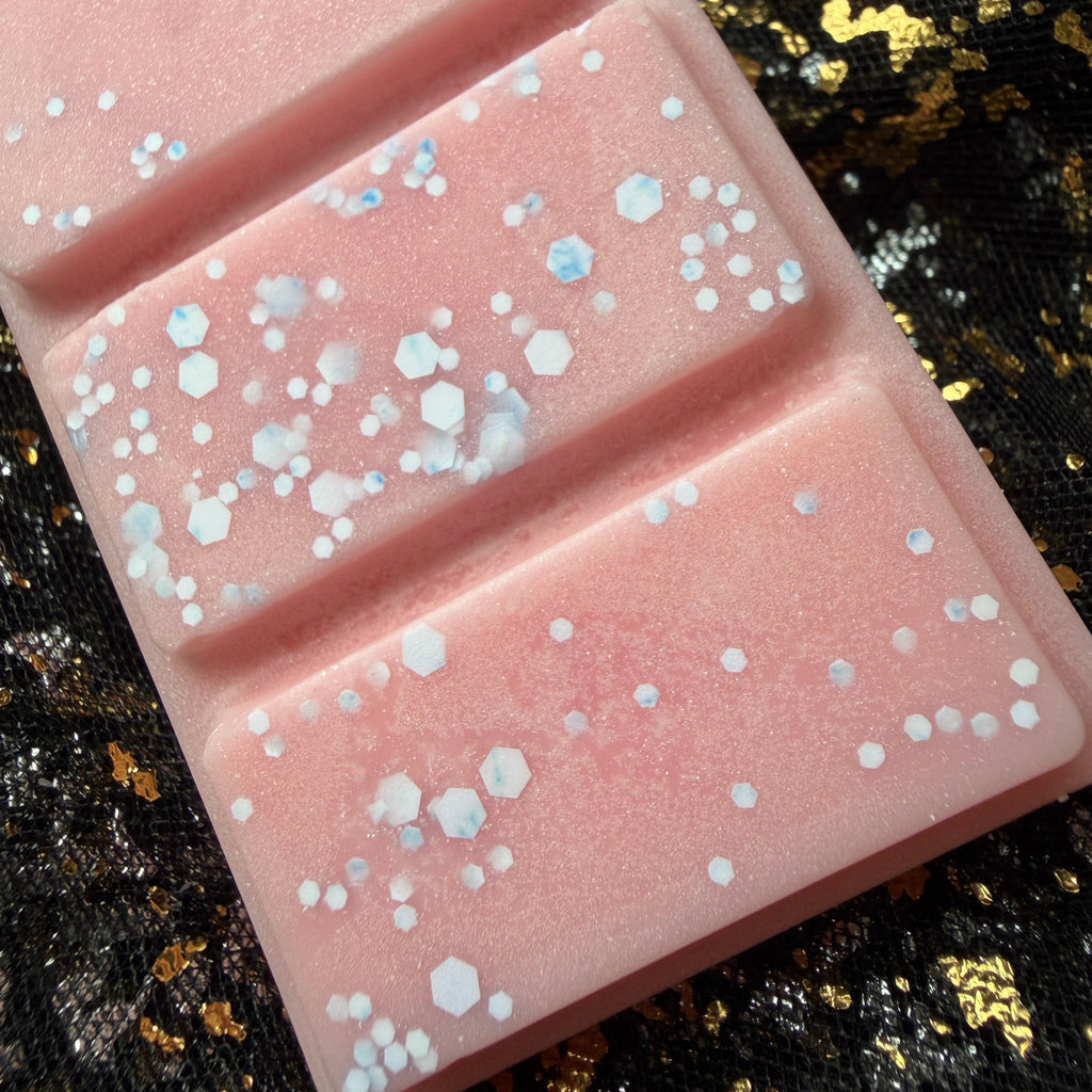 Close-up of Petals of the Seer floral long scented soy wax melt segments showing fine silver glitter and small iridescent pieces against soft pink wax.