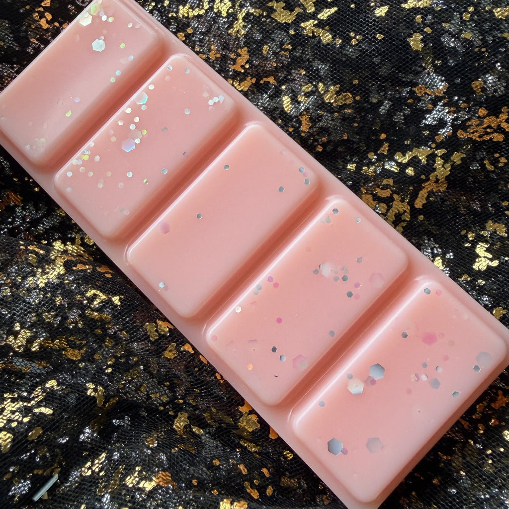 Angled photograph of the Peachy Keen peach scented long lasting soy wax melt showing all five peach-pink segments and scattered silver, pink and iridescent glitter.