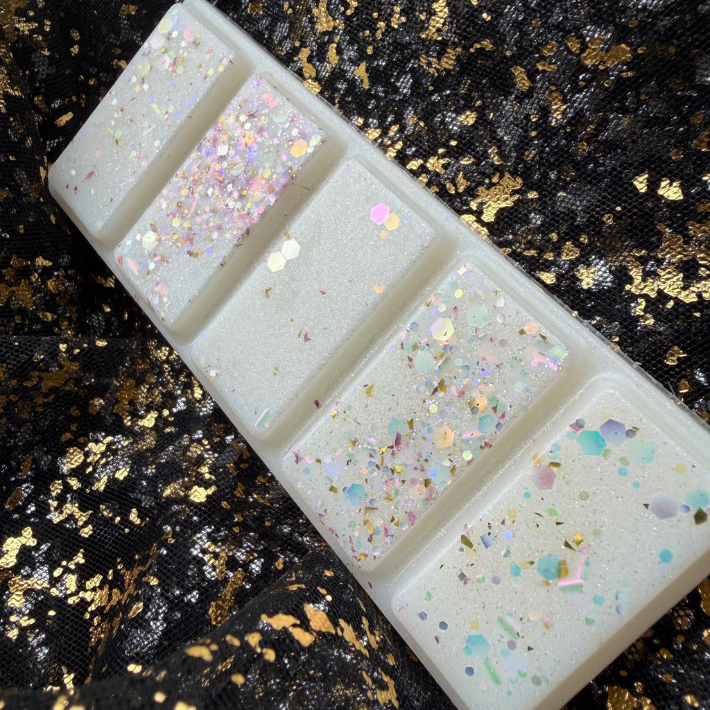 Angled close-up of the cream and white coloured handmade Baby Mine baby powder soy wax melt showing its segmented shape and pearl and silver  glitter finish.