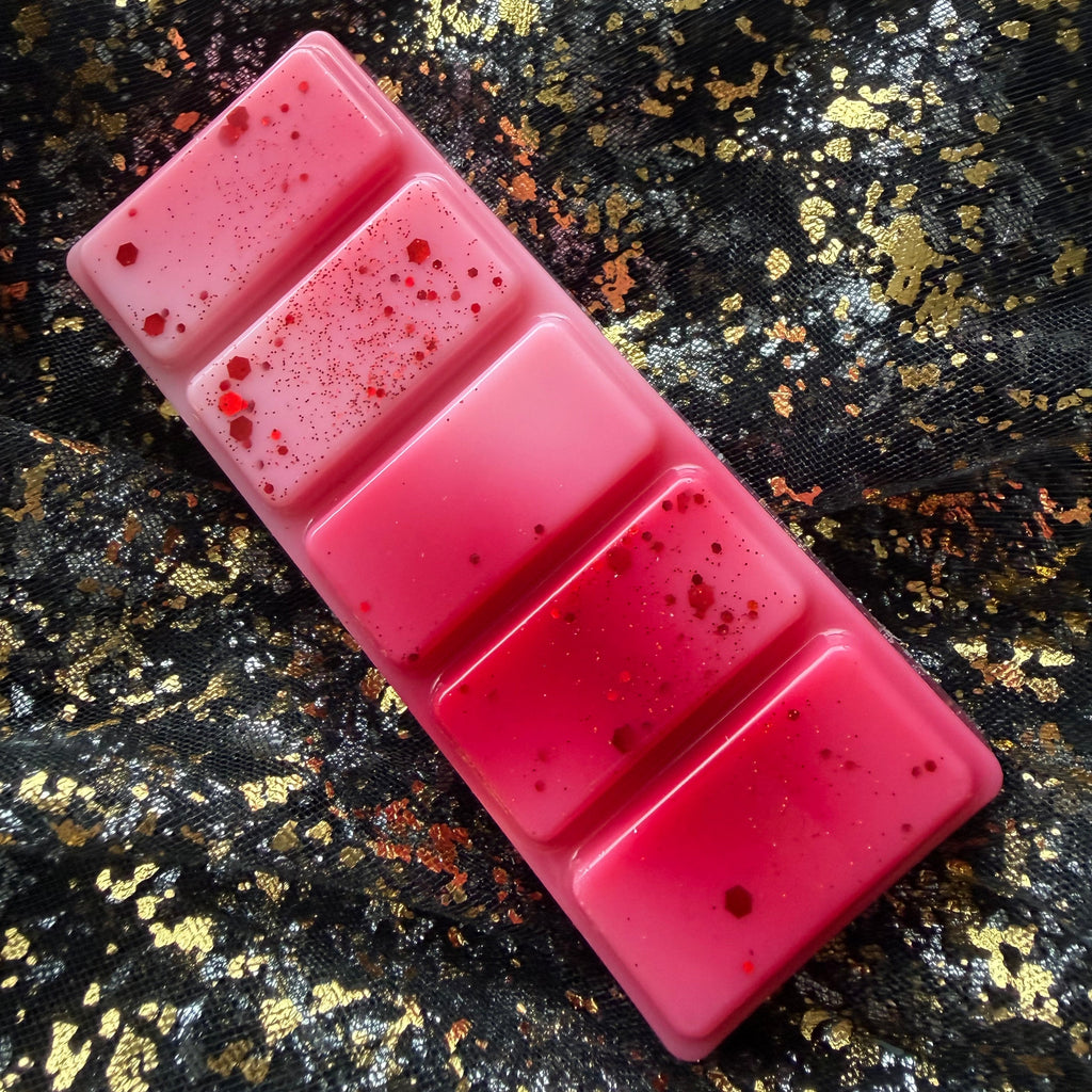 Angled close-up of the Fated Mates scented wax melt showing its pink, red and white segmented bar and decorative red finish.