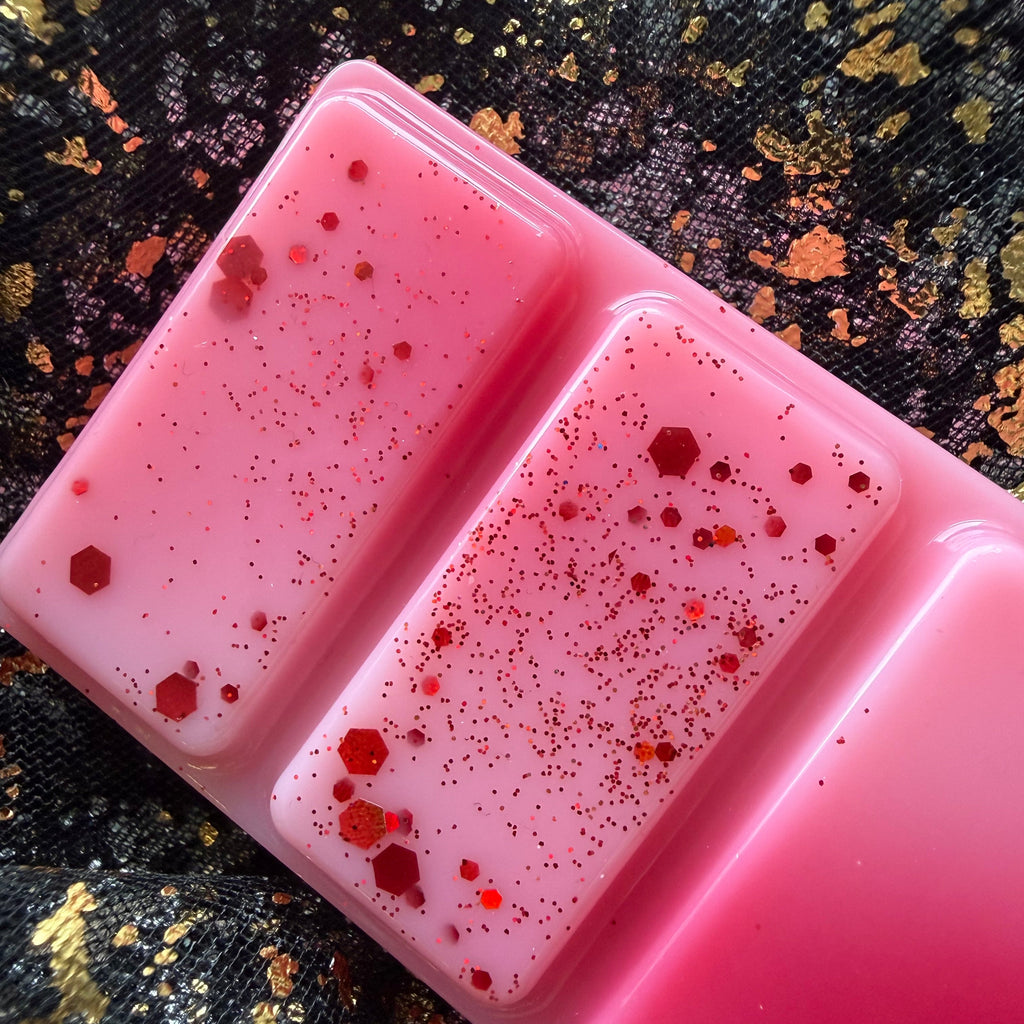 Close-up of the red and pink Fated Mates romantasy-inspired wax melt with red decorative detailing on black and gold fabric.