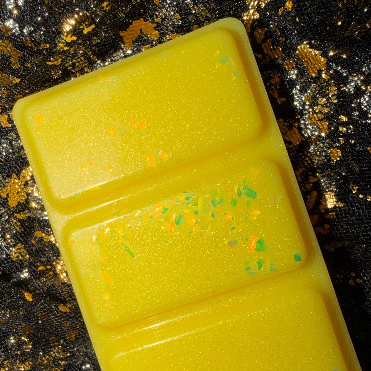 Angled close-up of the yellow Sherbet Lemon scented wax melt showing its segmented shape and decorative finish.