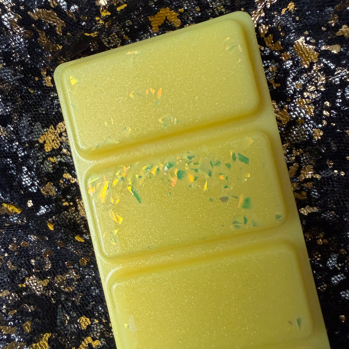 Close-up of the yellow glittery Sherbet Lemon soy wax melt segments with decorative shimmering flakes and a zesty lemon fragrance.