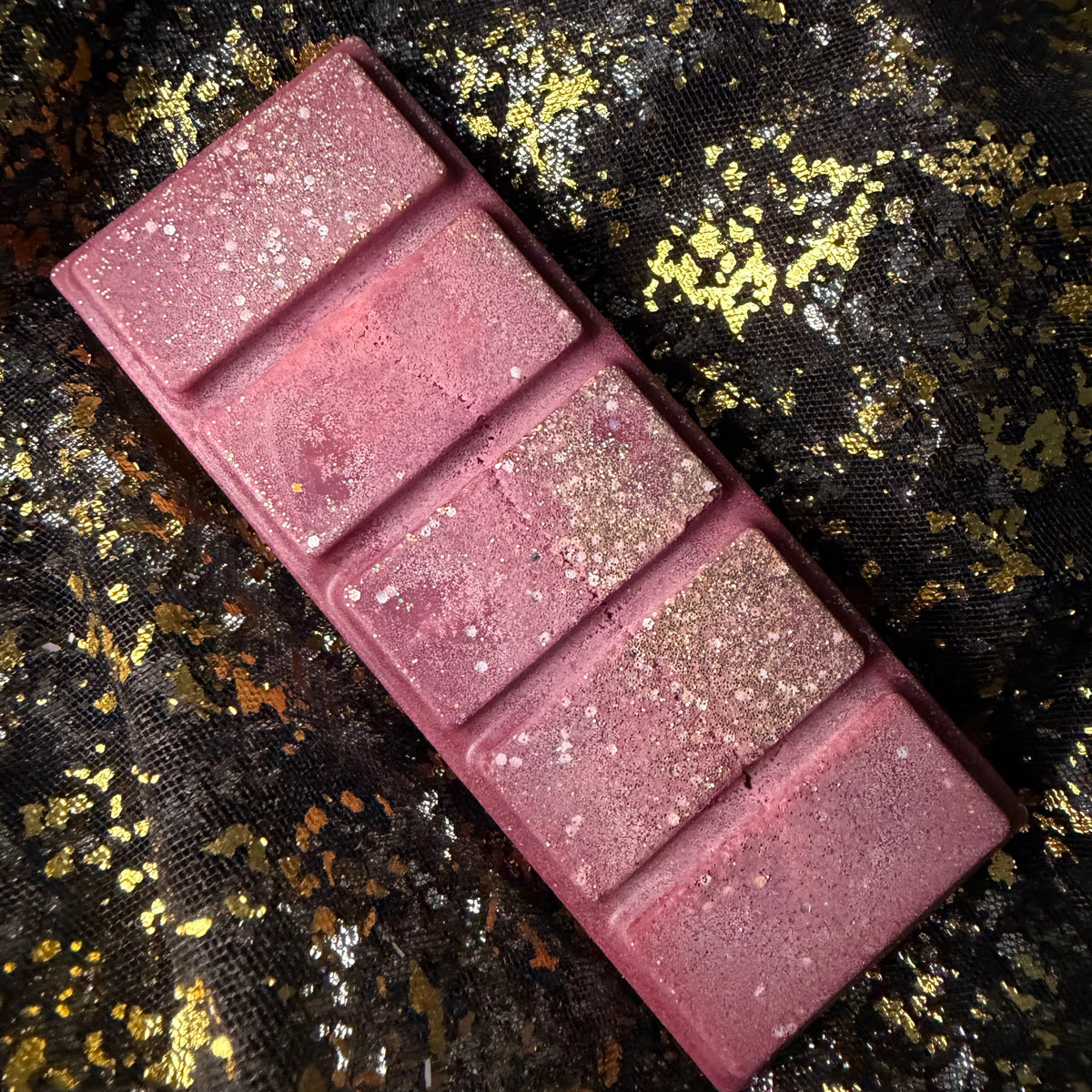 Unwrapped burgundy Cherry Bomb five-segment wax melt with sparkling glitter and a cherry liqueur and almond fragrance.