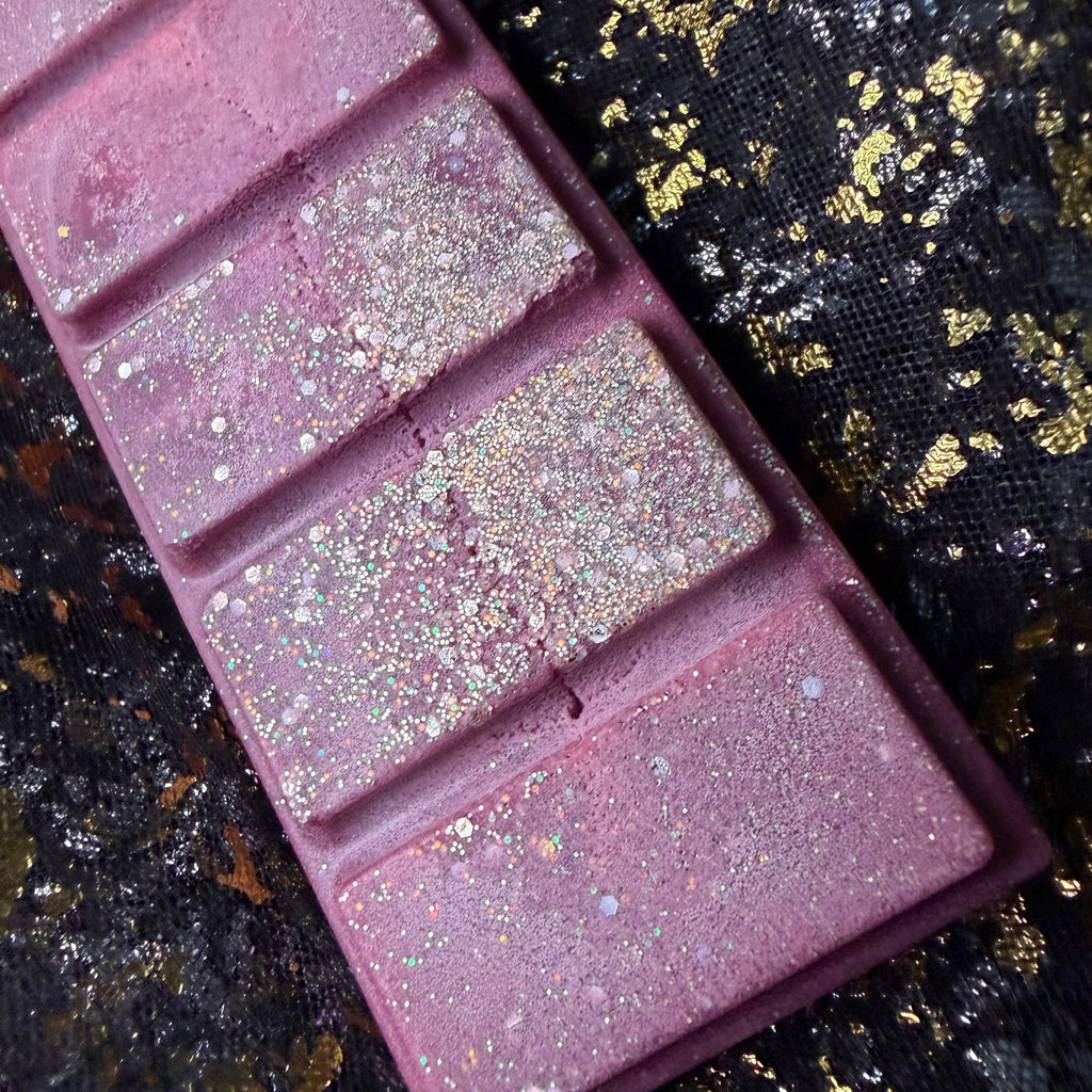 Angled close-up of the Cherry Bomb wax melt showing its glittering burgundy segments, handmade in Yorkshire. Waxident showing where there is frosting of the discounted soy wax. 