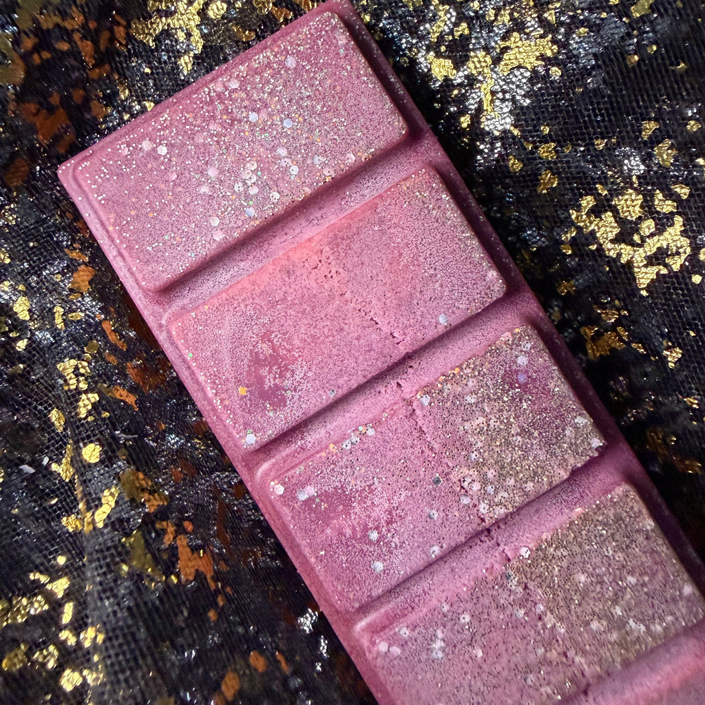 Close-up of the burgundy Cherry Bomb scented wax melt segments decorated with shimmering holographic glitter. Showing soy frosting on the discounted wax melt 