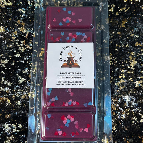 Bryce After Dark romantasy-inspired wax melt, showing a deep berry-purple five-segment soy wax bar decorated with red, pink and blue heart-shaped glitter inside a clear labelled clamshell on black-and-gold fabric.